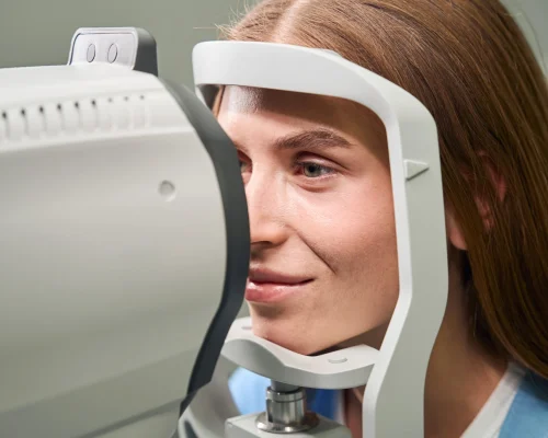 Young woman positioned for an automated eye test, using advanced ophthalmic equipment for detailed diagnostics